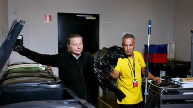 Två personer i miljörum, sorterar plast vid kärl