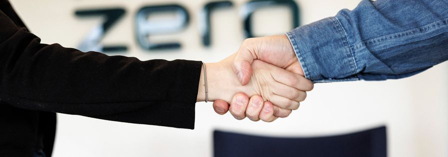Händer som skakar hand. I bakgrunden syns en vägg med PreZero-logotyp.