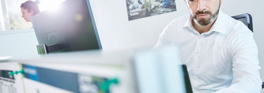 Employee work on computer and in the background is a PreZero poster