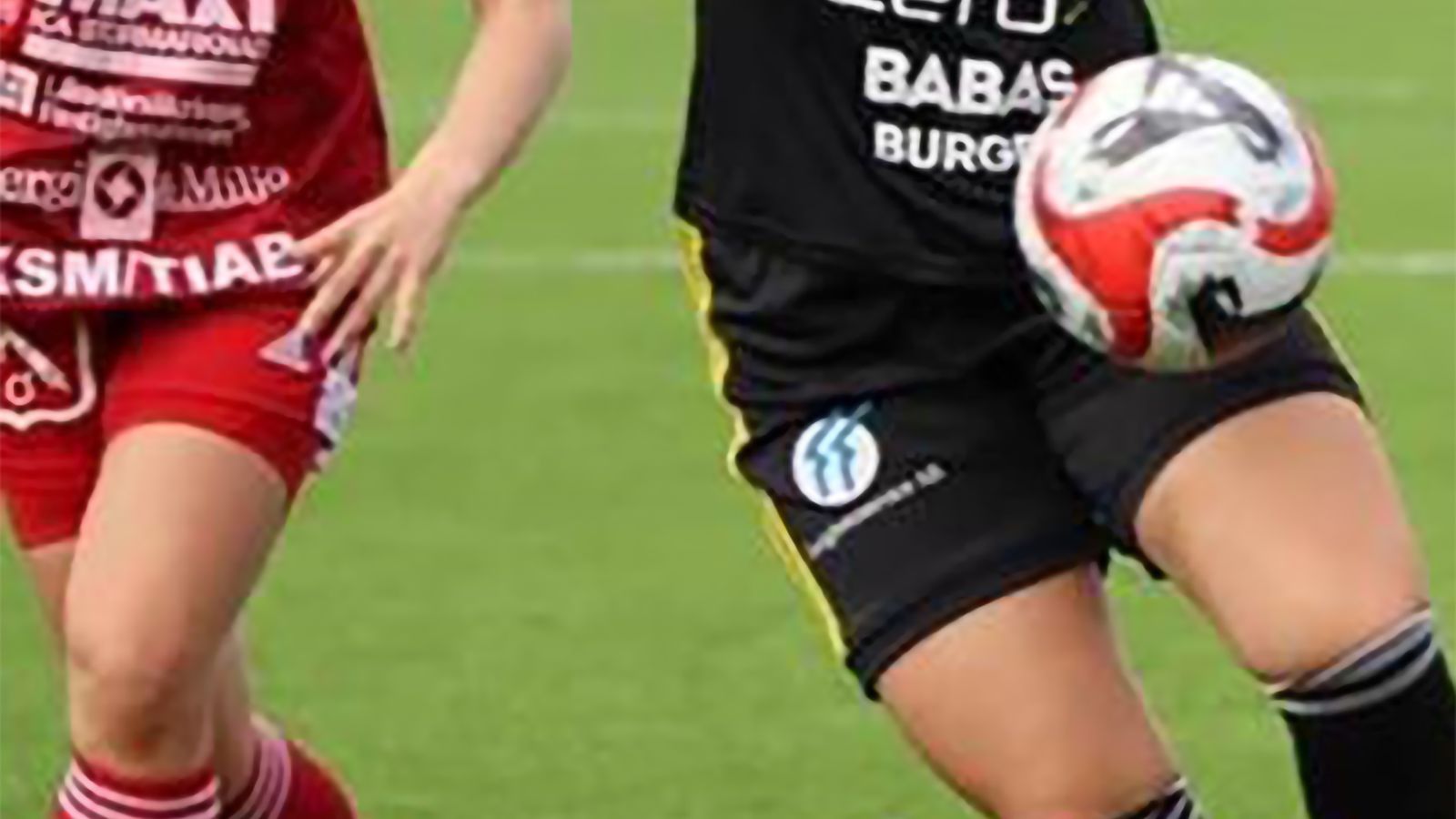 Överkropp och ben på två ungdomar från olika fotbollslag, med fotboll