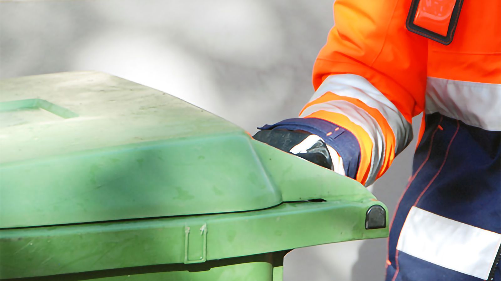 Detalj av person som hämtar grönt avfallskärl