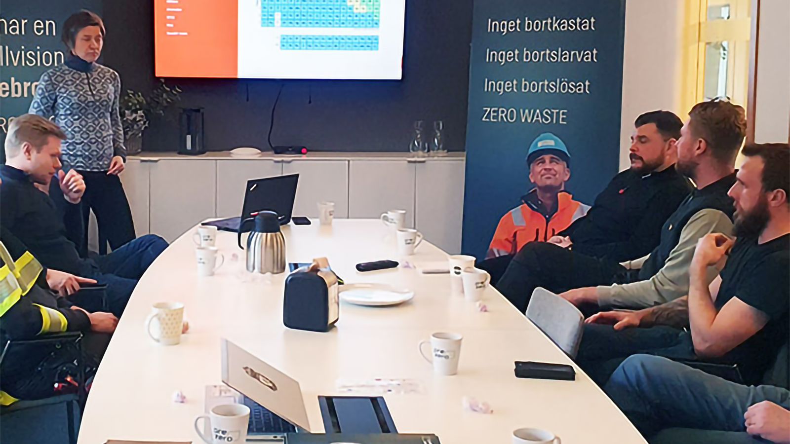 Utbildning i konferensrum, kursledare står vid konferensbordets kortsida och kursdeltagare sitter runt bordet