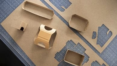 Zu sehen sind braune Faltschachteln aus Silphie-Papier auf einem Tisch aus der Vogelperspektive