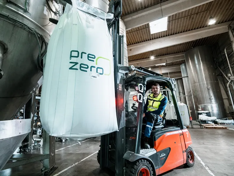PreZero Mitarbeiter bedient Gabelstapler mit prezero Big Bag in Industriehalle
