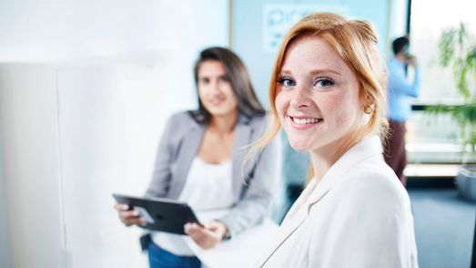 Two employees watching, one with tablet in her hand