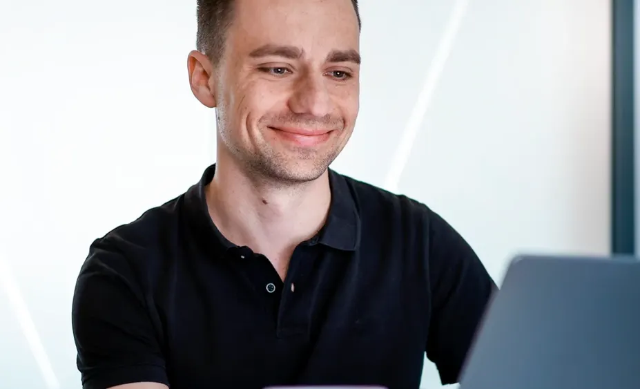 Lächelnder Teilnehmer verfolgt ein Online-Event zur Kreislaufwirtschaft am Laptop