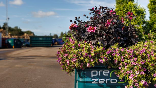 Blomsterarrangemang i grönt kärl med PreZero-logotyp på