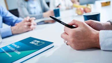In the foreground is a PreZero pen and book. In the background you can see a discussion group