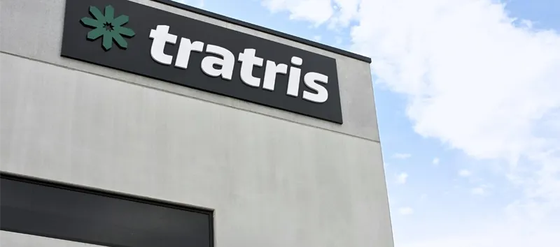 Betongebäude-Ecke mit einem schwarzen Firmenschild, grünem Sternlogo und weißem Text 'tratris'