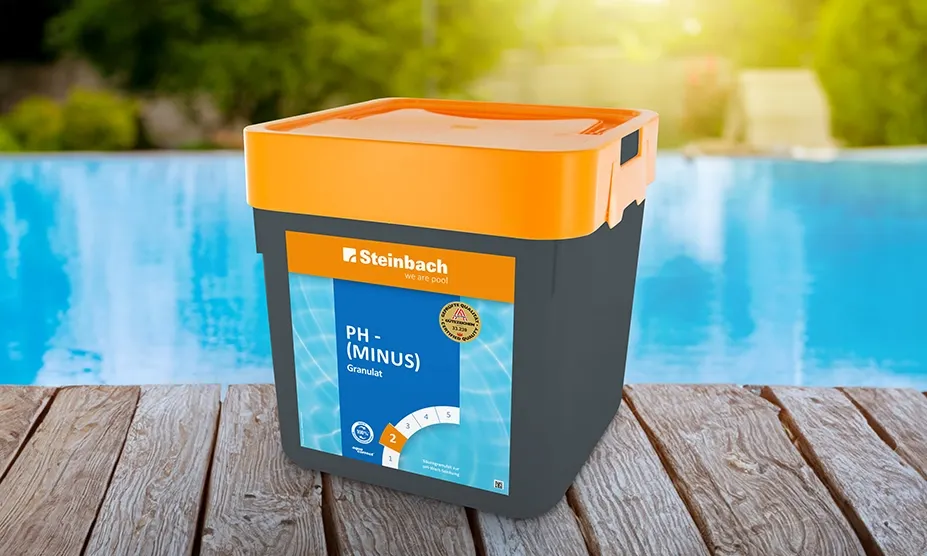 Grauer Eimer mit orangefarbenem Deckel "Steinbach pH-Minus Granulat" auf Holzterrasse am Pool.