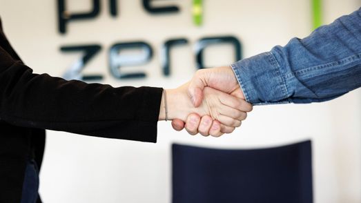Händer som skakar hand. I bakgrunden syns en vägg med PreZero-logotyp.