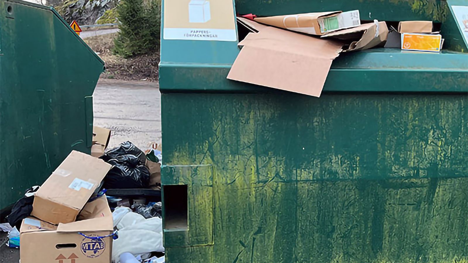 Överfylld container med avfall på marken, utanför containern