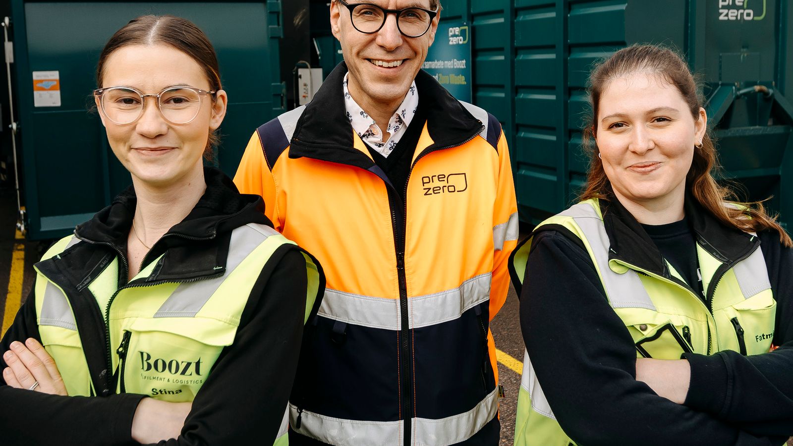 Tre personer, en PreZero-anställd och två anställda på Boozt stående framför gröna containrar