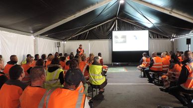 Personnel de Lamesch en gilets de sécurité assistant à une formation sur la sécurité au travail sous un chapiteau.
