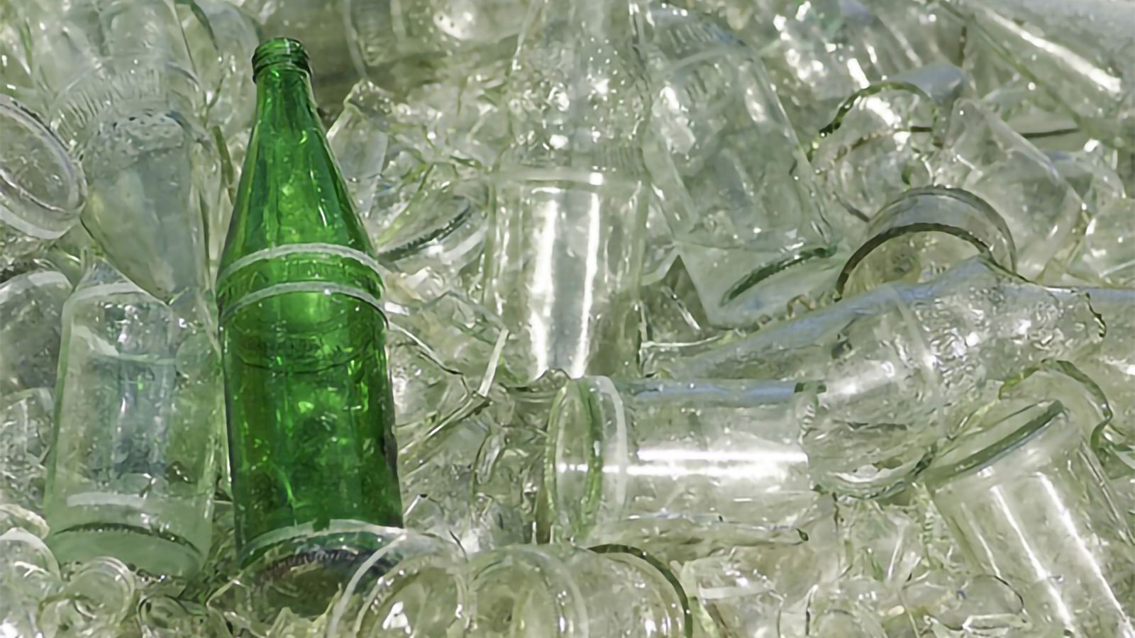 Grön glasflaska bland ofärgat glasavfall