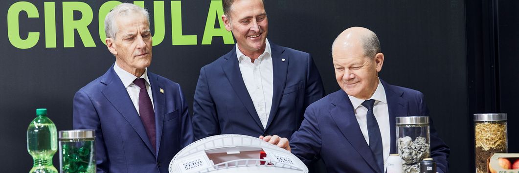 Drei Herren schauen sich ein Modell der PreZero Arena an, das auf einem Tresen vor ihnen steht