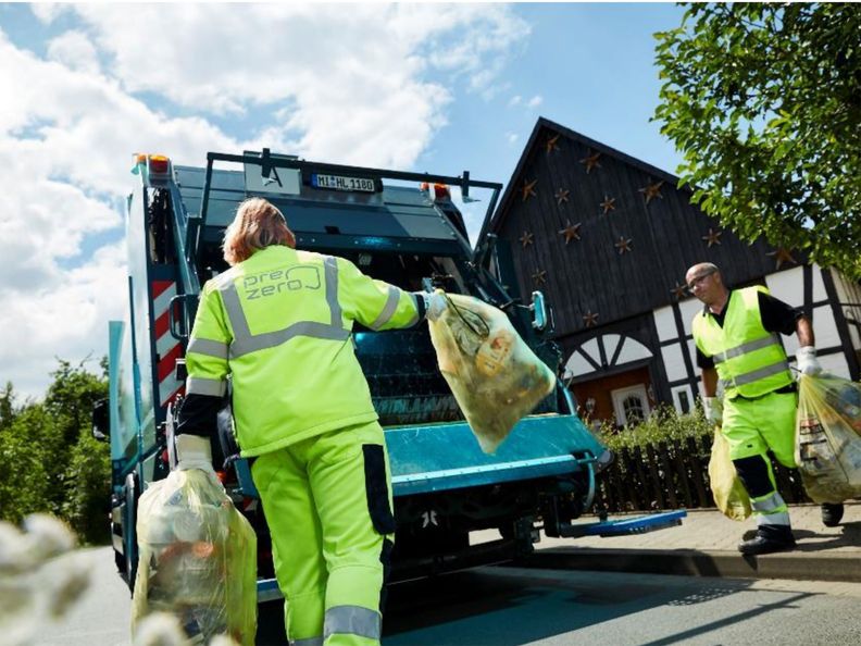 Miljöarbetare i Tyskland som bär sopsäckar till sopbil