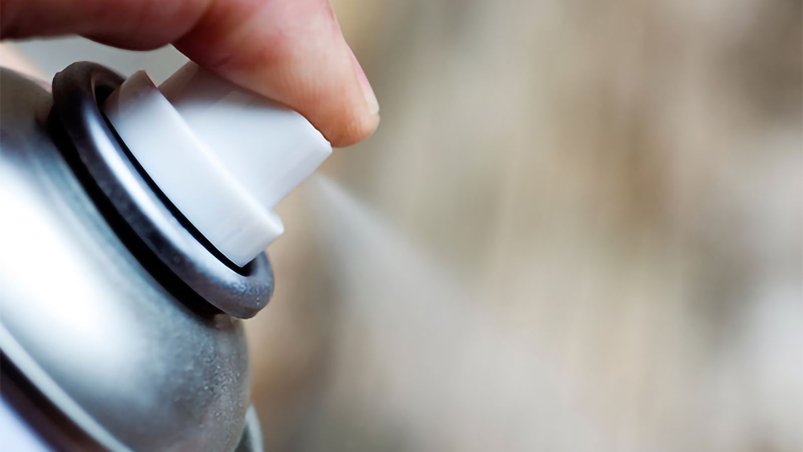 Toppen av sprayburk, finger som trycker ner knappen och sprayar