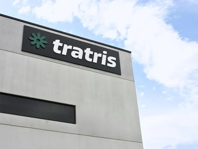 Betongebäude-Ecke mit einem schwarzen Firmenschild, grünem Sternlogo und weißem Text 'tratris'