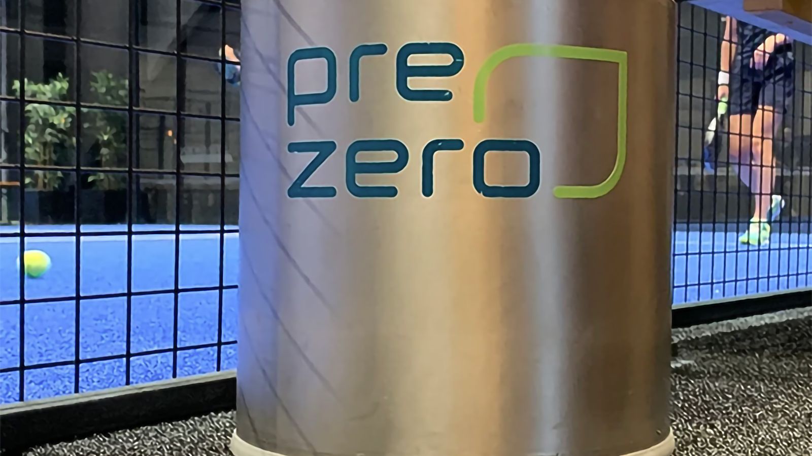 Tryckbehållare med PreZero-logotyp på, stående vid padelbana