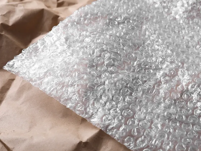 PreZero Verpackungsmaterialien: Transparente Luftpolsterfolie aus Kunststoff und braunes Packpapier für sicheren Versand und Lizenzierung.