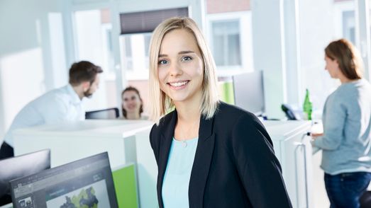 Employee watching and in the background are people and a desktop