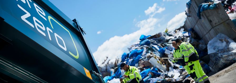 Employees next to mountain full of plastic waste and in front of a PreZero vehicle
