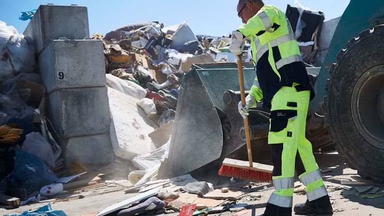 Waste disposal yard employee with broom