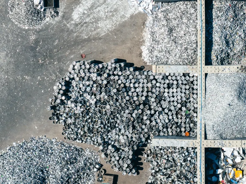 Luftaufnahme eines Recyclinghofs mit einem großen Haufen Alufelgen und Bergen aus Metallschrott