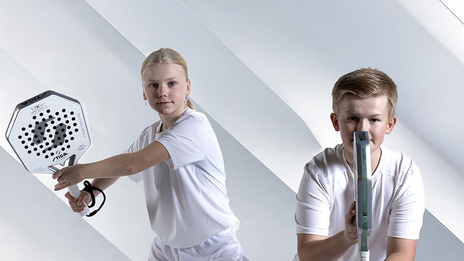 Tjej och killa som står beredda med sina padelrack