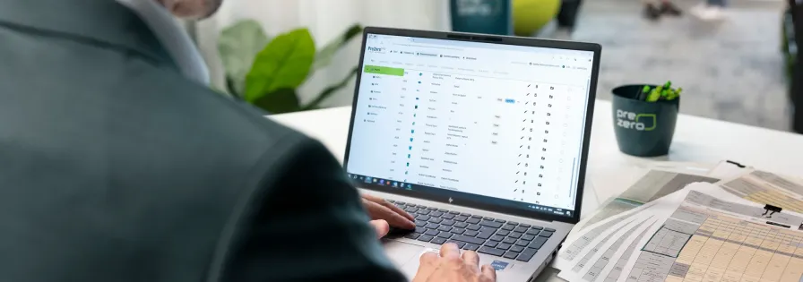 Employee using the PreZero digital platform on a laptop for waste management and recycling process tracking in a professional office setting