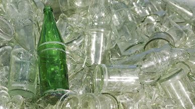 Grön glasflaska bland ofärgat glasavfall