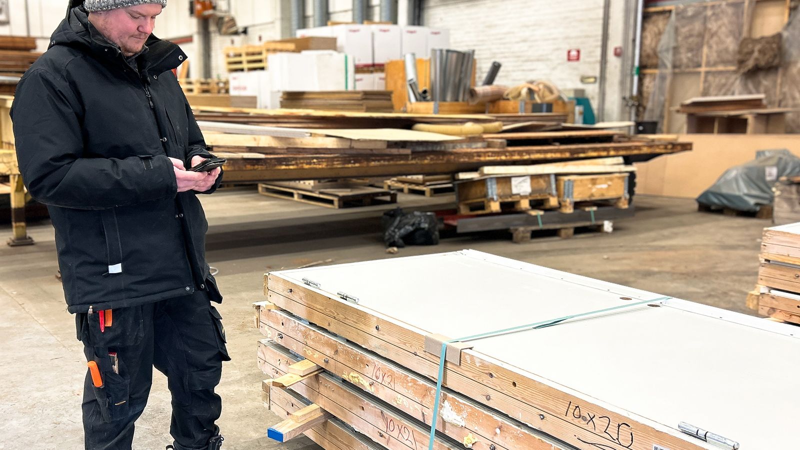 Person som står vid hög med dörrar, och tittar ner på sin mobil