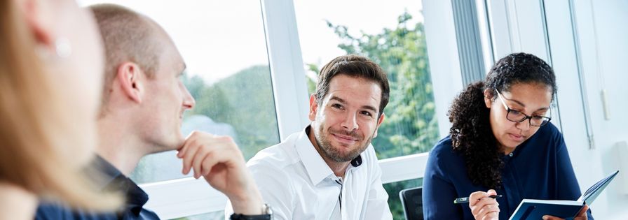 Four employees discussing in a meeting room and on the table PreZero cup