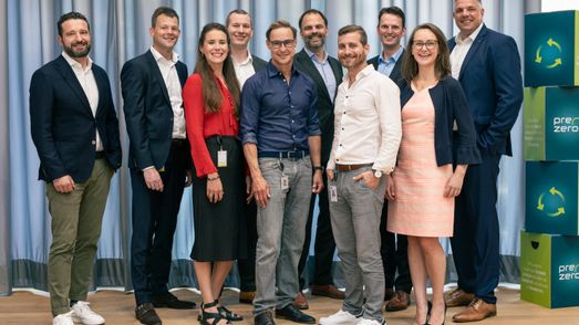 10 Menschen stehen zusammen für ein Gruppenfoto und lächen in die Kamera