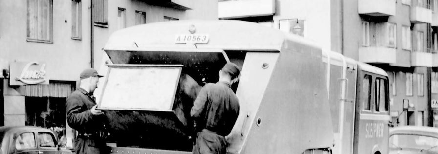 Svart vit bild på två miljöarbetare från förr på flak på bakre delen av lastbil