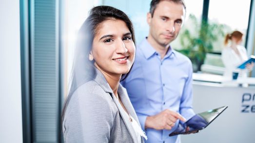 Two employees watching, one with tablet in his hand
