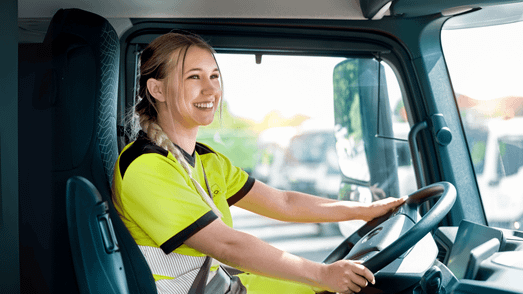 Berufskraftfahrerin am LKW-Lenkrad sitzend.