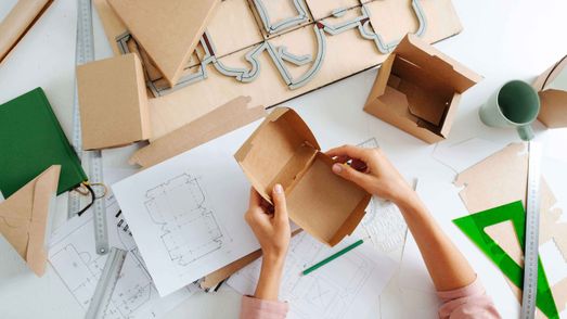 Verpackungen aus Pappe werden an einem Zeichentisch designed