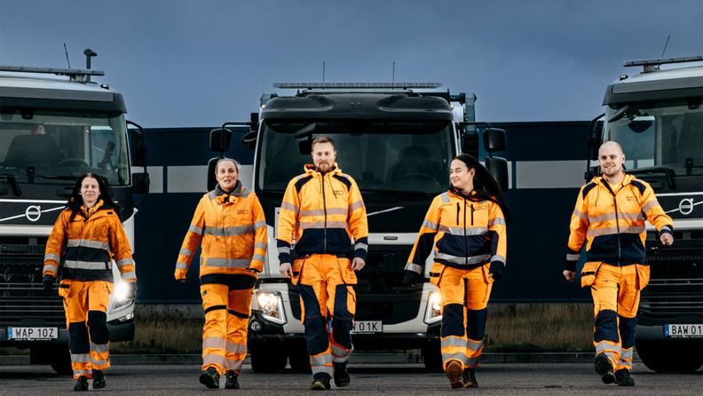 Miljöarbetare från PreZero gående framför parkerade lastbilar