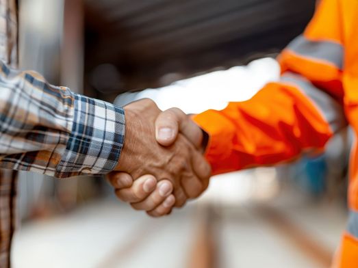 [AI-genererad] Handskakning mellan man med rutig skjorta och man med varselkläder