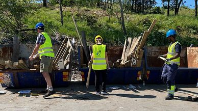 Människor i säkerhetsvästar och hjälmar som sorterar brädor