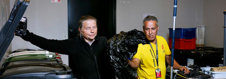 Två personer i miljörum, sorterar plast vid kärl