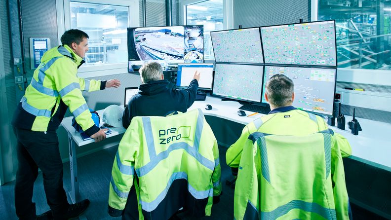 Employees look at screens in control room