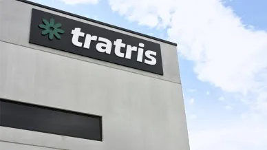 Betongebäude-Ecke mit einem schwarzen Firmenschild, grünem Sternlogo und weißem Text 'tratris'