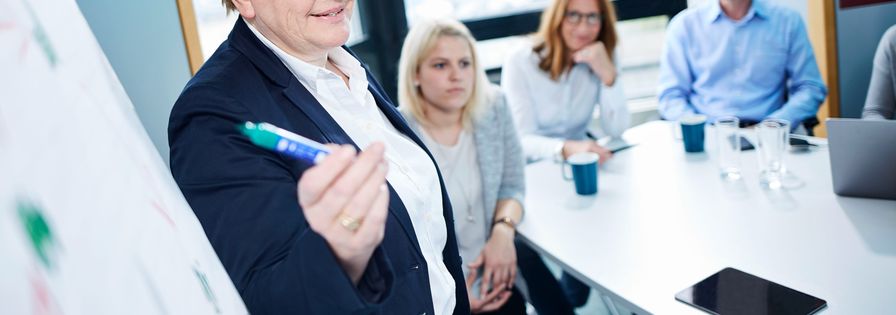 Frau mit Stift zeigt auf ein Plakat PreZero