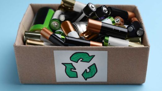 Altbatterien in einem Sammelkarton mit Recyclingsymbol