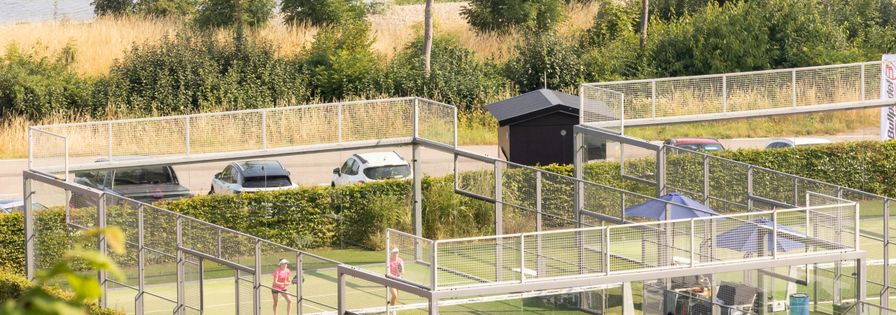 Padelbana vid strandkant med fyra spelare, sedda på avstånd