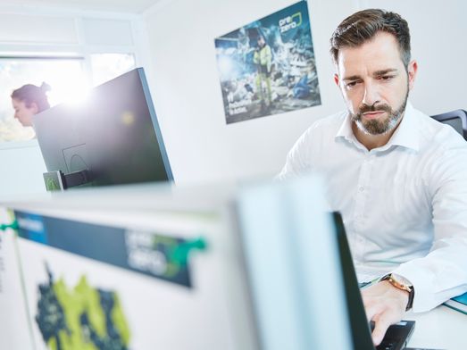 Employee work on computer and in the background is a PreZero poster