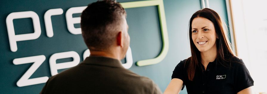Två glada personer tar i hand, i mötesrum